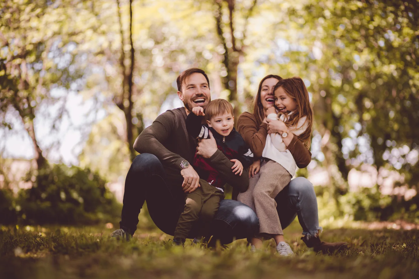 Eine Familie mit Kleinkind sitzt zusammen unter blühenden Bäumen
